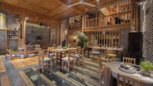 A rustic interior with wooden beams, brick walls, and a variety of seating arrangements. - Mengqi Xiaozhu Inn (Zhenyuan County)