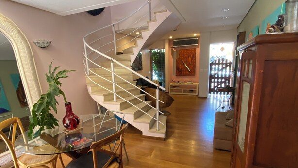 A modern interior with a spiral staircase, a dining area with a glass table, and a wooden cabinet.