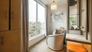 A modern room with a large window, a chandelier, a unique wall art piece, and a seating area.