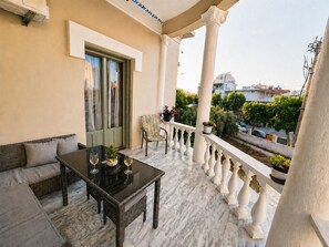 A balcony with a sofa, a table with glasses, and potted plants.