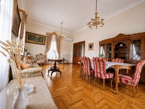 A dining area with a wooden table and chairs, a chandelier, and a painting on the wall.