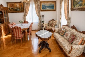A traditional room with a dining table, chairs, a sofa, and a floor lamp.