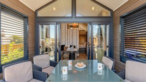 A modern interior with a glass-top table, wicker chairs, and a view of a pool and outdoor area.
