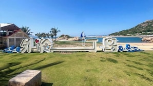 Une vue sur la plage avec un panneau arborant un texte stylisé et un palmier.