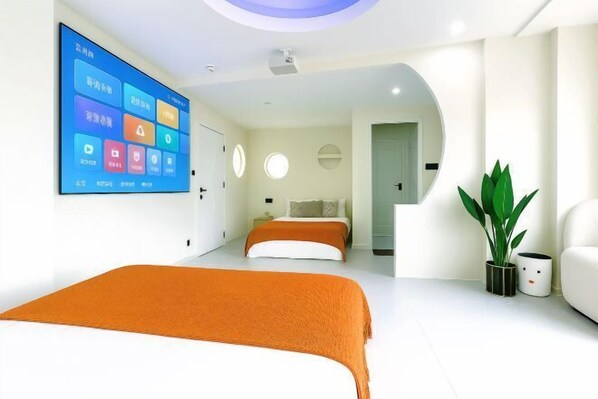 A modern hotel room with a large bed, a flat-screen TV, a potted plant, and a white sofa. - Lanjingge Inn (Zhuhai)