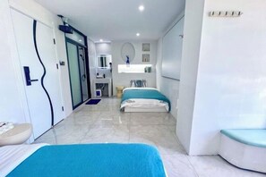 A modern hotel room with a large bed, a separate seating area, a bathroom with a mirror, and a small kitchenette. - Lanjingge Inn (Zhuhai)