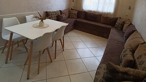 A modern living room with a dining area, featuring a sectional sofa, a dining table with chairs, and recessed ceiling lighting. - Modern apartment near beaches and airport (Tetuán)