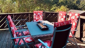 Una terraza al aire libre con una mesa y sillas, rodeada de árboles.