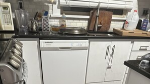 A kitchen with white cabinets, a dishwasher, a microwave, and a wooden floor.