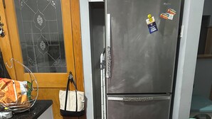 A compact kitchen with a refrigerator, wooden flooring, and a door with decorative glass.