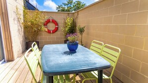 Un patio con una mesa, sillas, una planta en maceta y un anillo salvavidas rojo en la pared.