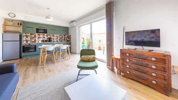 Una cocina moderna con comedor, televisor y un amplio ventanal.
