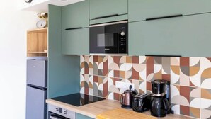 Una cocina moderna con microondas, cafetera y tostadora sobre la encimera, y un reloj en la pared.