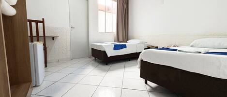 A hotel room with two beds, a window with curtains, a door, and a ceiling fan.