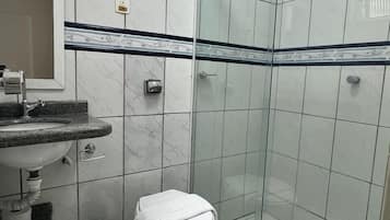 Un baño con ducha de vidrio, un lavamanos con encimera de mármol y un inodoro.