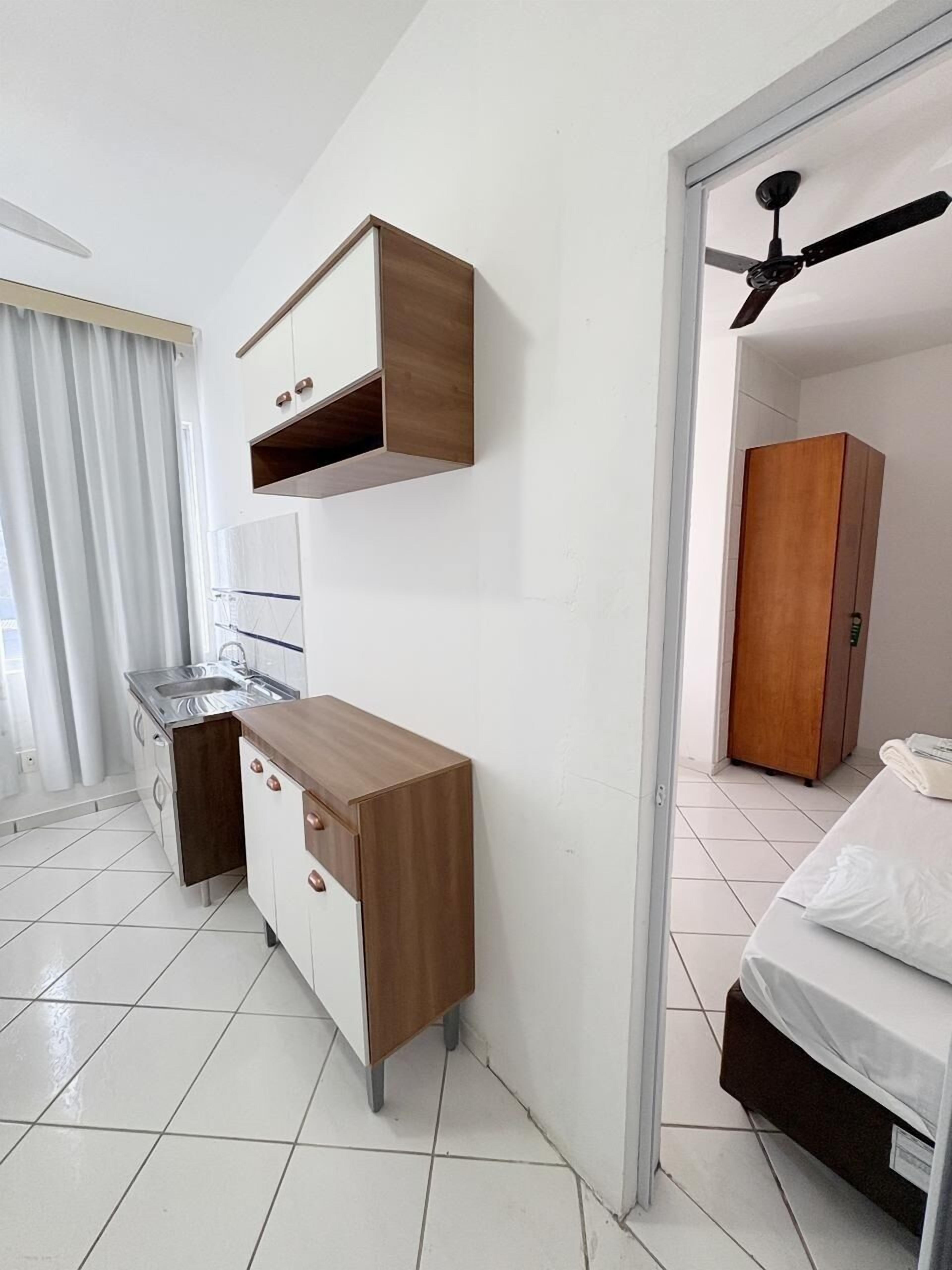 Una stanza compatta con angolo cottura, un letto, un armadio e una ventola a soffitto.