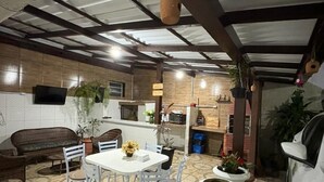A covered outdoor dining area with a table and chairs, potted plants, and a white car parked nearby. - Big Hotel - Florianopolis continental (Florianopolis)