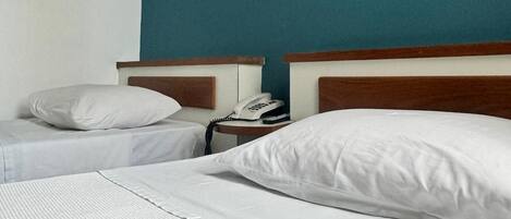 A hotel room with two beds, a painting on the wall, and a telephone on the nightstand.