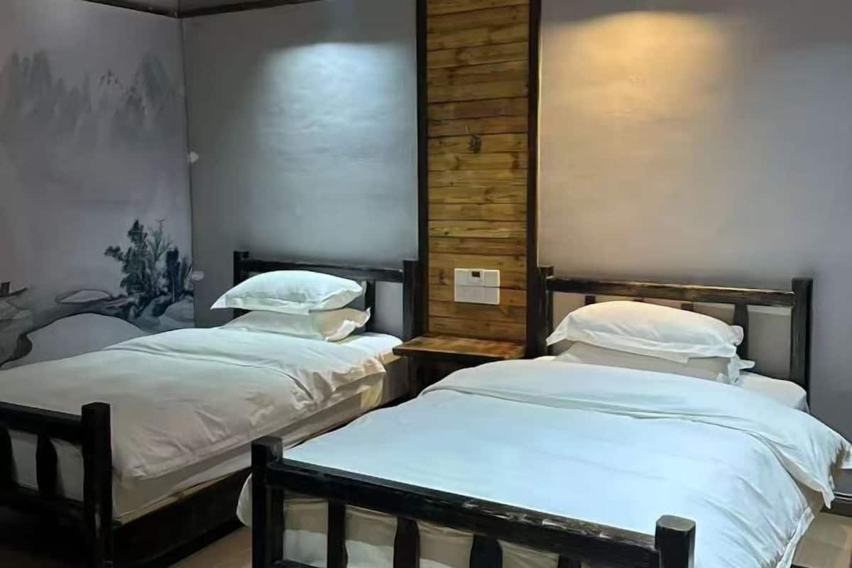 A room with two single beds, a wooden accent wall, and a mural on the left wall.