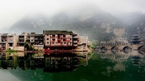 Un bâtiment traditionnel à étages, dont l’image se reflète dans l’eau.