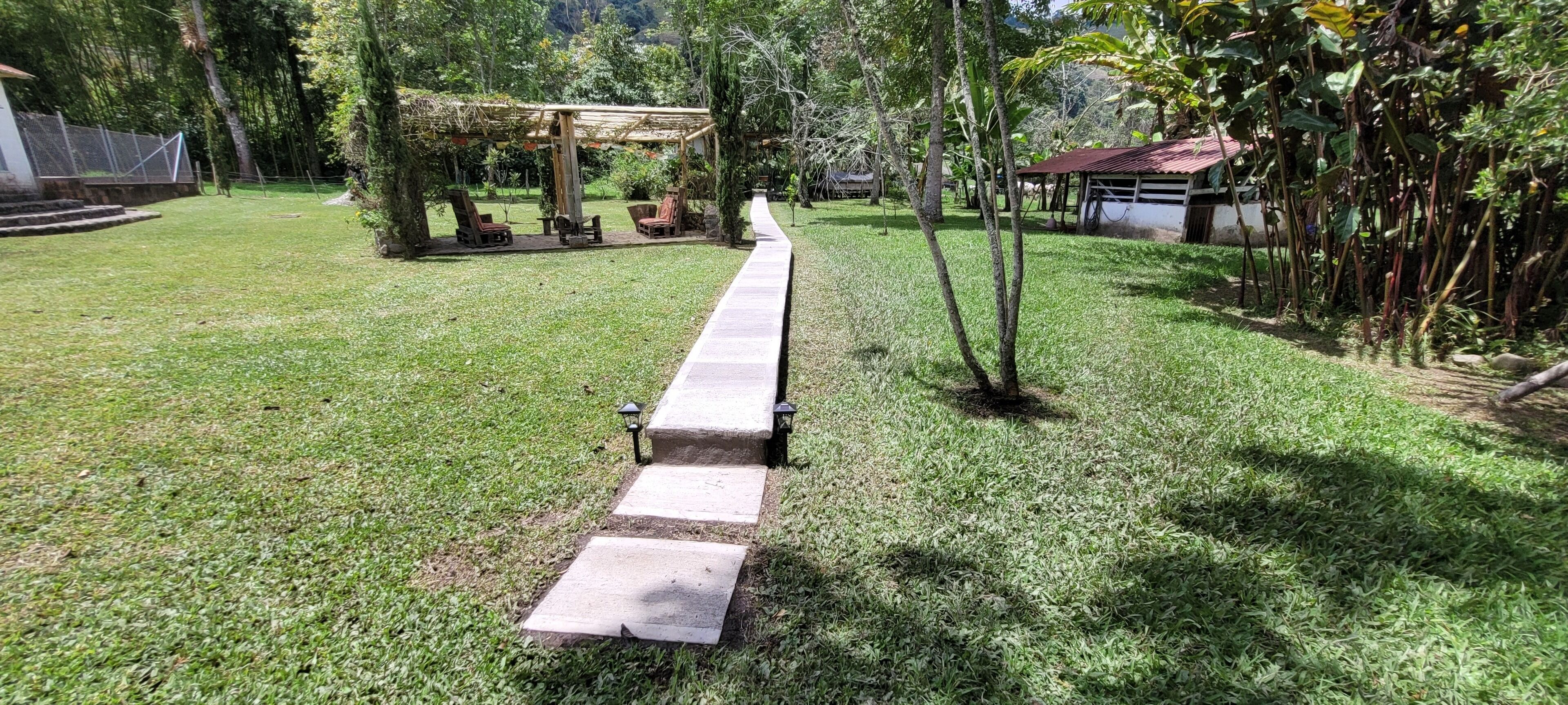 Un jardin avec un sentier, des chaises et une pergola.