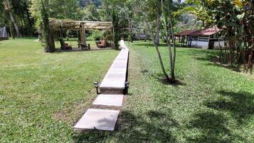 Un jardin avec un sentier, des chaises et une pergola.
