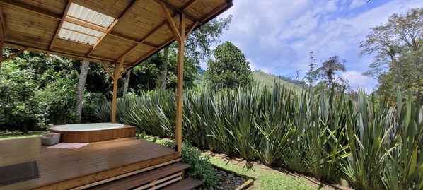A wooden deck with a hot tub, surrounded by lush greenery and a mountainous backdrop. - Exclusivo Cocora con jacuzzi salento (Salento)