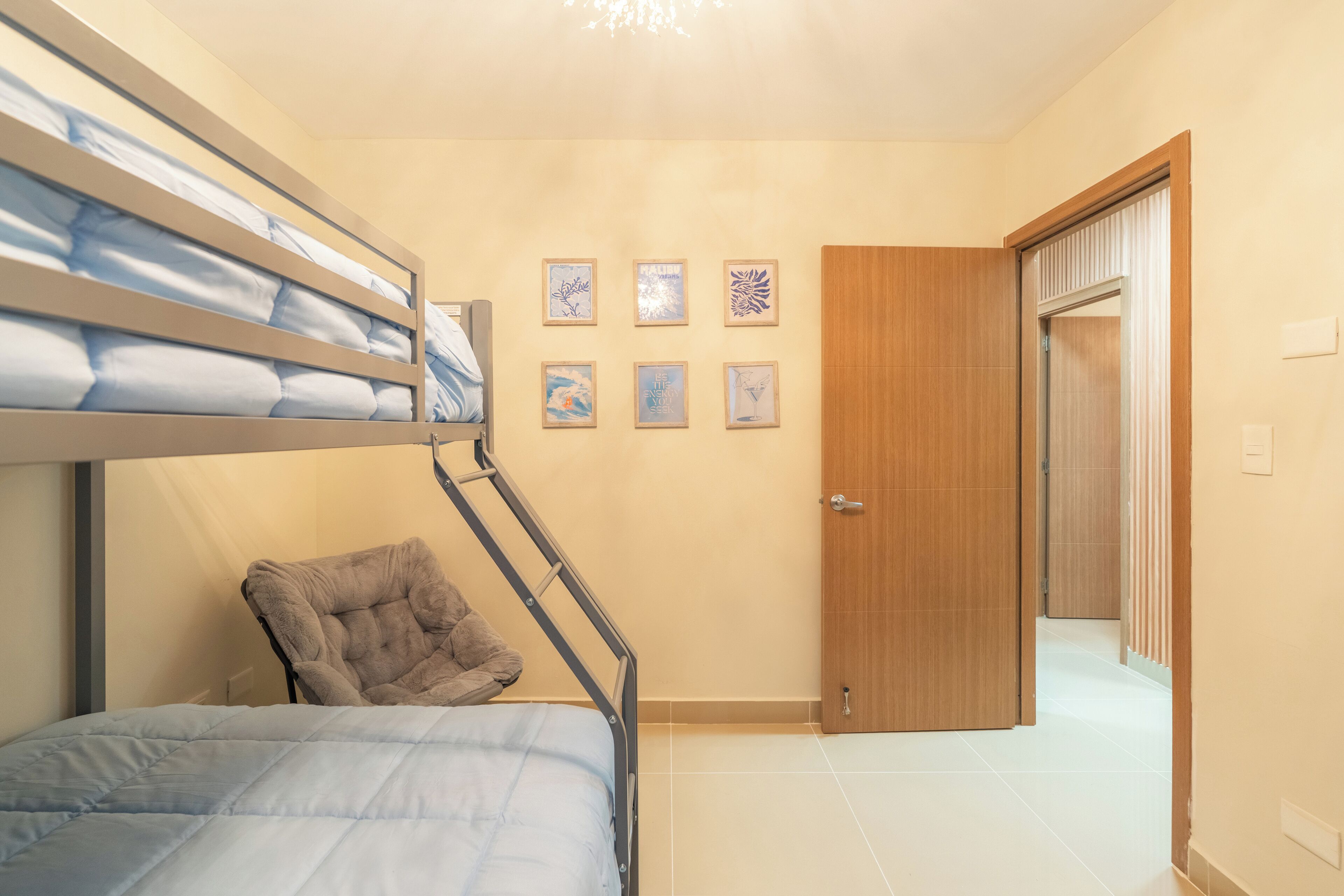 Ein Schlafzimmer mit Etagenbetten, einem Sessel, einer Tür und mehreren gerahmten Bildern an der Wand.