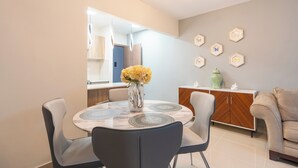 A modern dining area with a round table, chairs, and a vase of flowers.