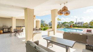An outdoor patio area with a pool, dining setup, and seating.