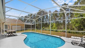 A covered swimming pool with a view of a forest and a building in the background. - 3-bedroom villa in fantastic Clermont that backs on to a Conservation Area (Clermont)