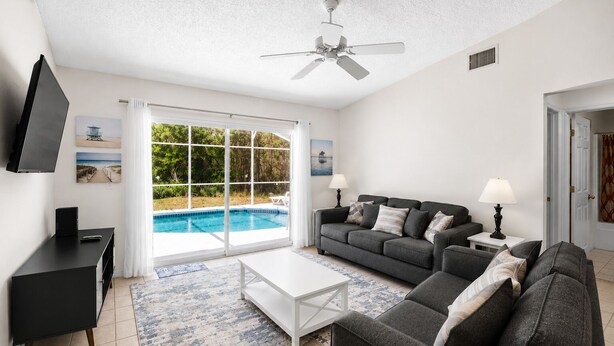 A living room with a pool, a sofa, a coffee table, a TV, and a ceiling fan. - 3-bedroom villa in fantastic Clermont that backs on to a Conservation Area (Clermont)