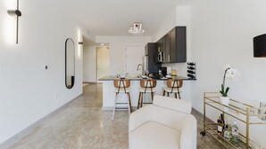 A modern kitchen with dark cabinets, a central island with bar stools, and a wine rack. - Lux Design Apartment near beach (Fort Lauderdale)