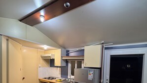 A compact kitchen with a wooden table, a refrigerator, and a window with a view. - Zielo Mobil Home (Tirig)