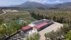 A building with a red roof and solar panels, surrounded by trees and a pool. - Zielo Mobil Home (Tirig)