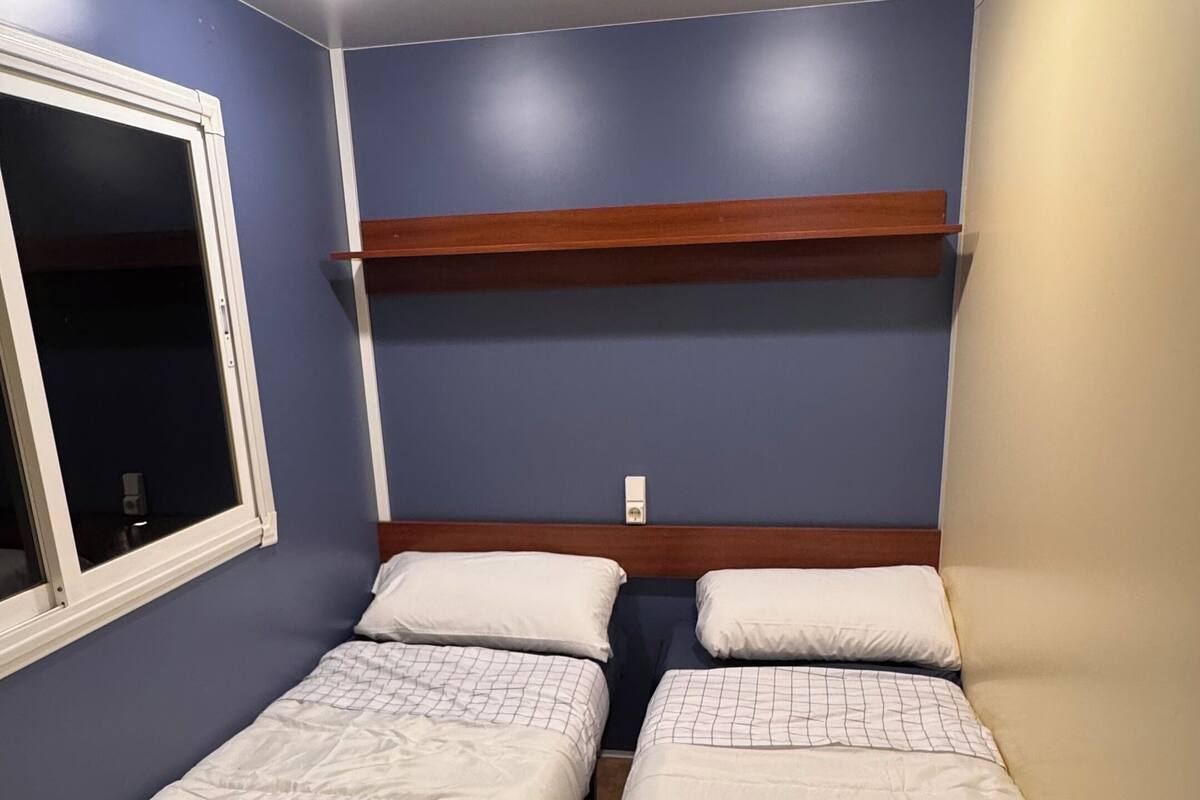 A room with two single beds, a window, and a built-in shelf.