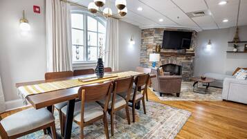 A dining area with a wooden table and chairs, a stone fireplace, and a television mounted on the wall.