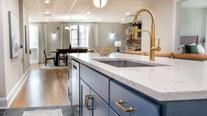 Een moderne keuken met een groot eiland, gouden kraanwerk en hanglampen.