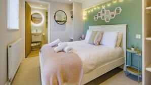 A neatly arranged bedroom with a bed, bedside tables, a mirror, and wall decorations.
