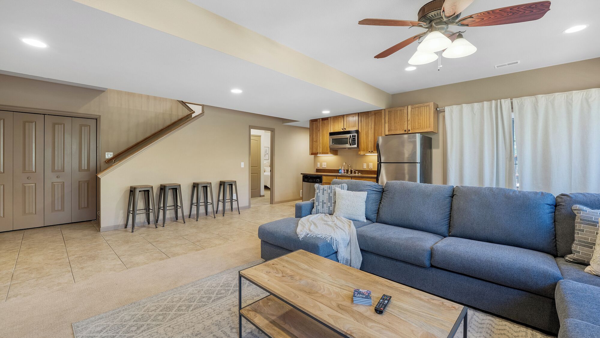 A modern living room with a blue sofa, wooden coffee table, and a ceiling fan.