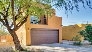 A residential building with a brown garage door, a tree in front, and a clear sky. - Desert Oasis Near Saguaro & Downtown (Tucson)