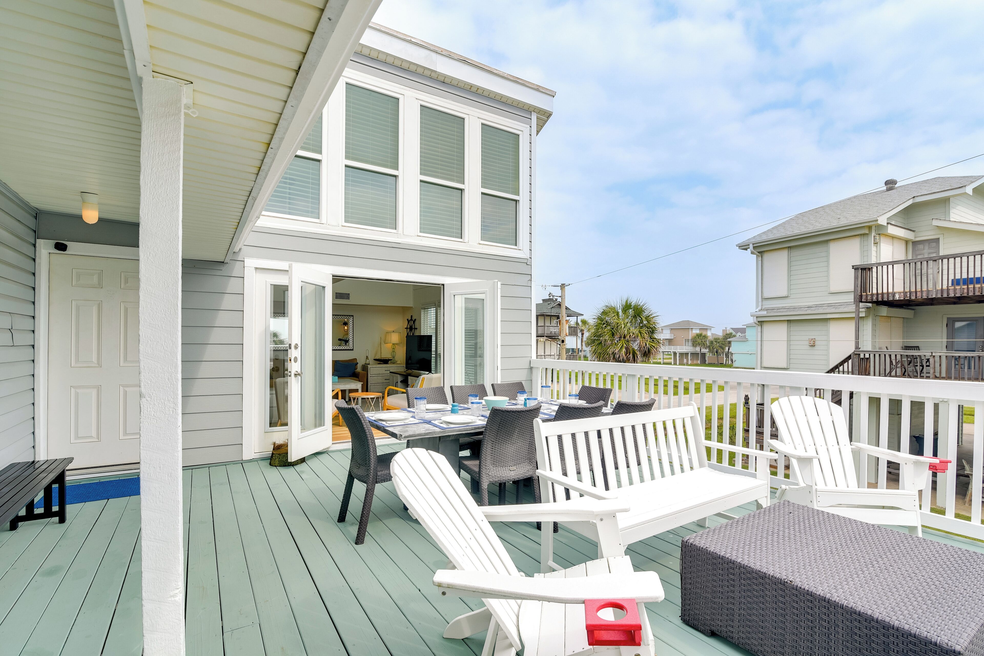 A covered outdoor deck with a dining table and chairs, a bench, and a wicker sofa.
