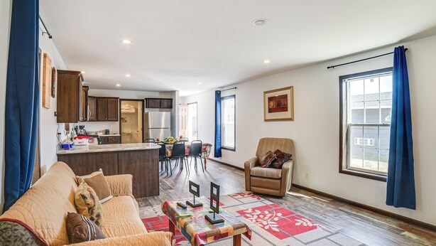 A living room with a sofa, a coffee table, and a rug. There is a kitchen in the background with cabinets and a refrigerator. - Dog-Friendly Miller Hunting Retreat! (Miller)