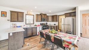 A modern kitchen with wooden cabinets, a central island, and a dining area with a table and chairs. - Dog-Friendly Miller Hunting Retreat! (Miller)