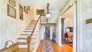 A grand staircase with a red patterned carpet leading to a second floor. - Historic & Spacious Family Home in Nicholasville! (Nicholasville)