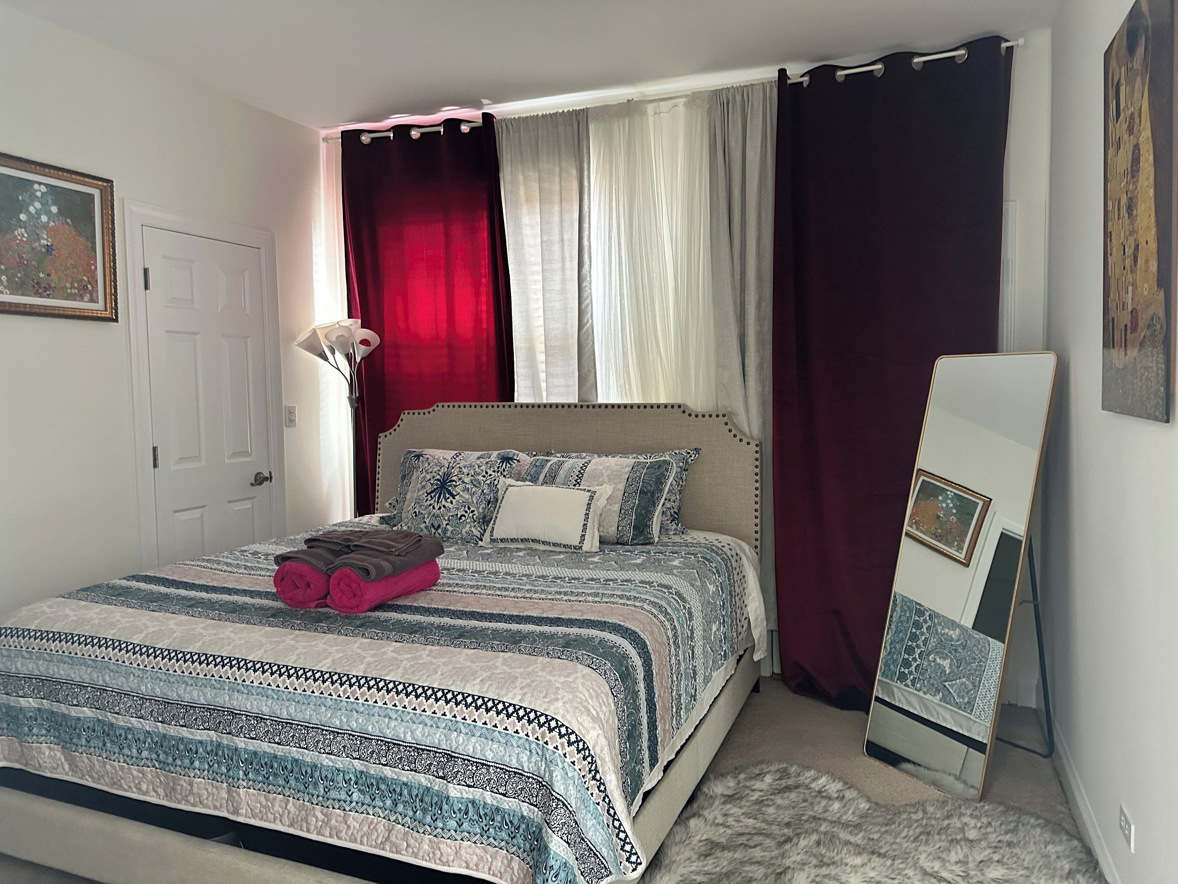 A neatly made bed with patterned bedding, a bedside lamp, and a framed picture on the wall.