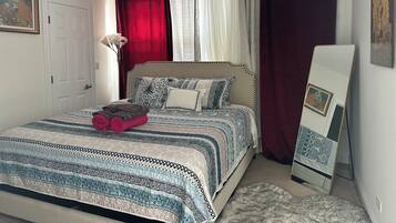 A neatly made bed with patterned bedding, a bedside lamp, and a framed picture on the wall.