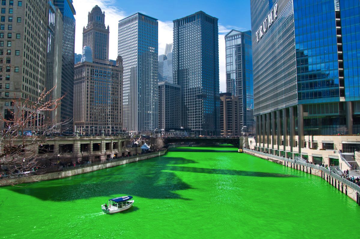 A river with green water, surrounded by tall buildings.