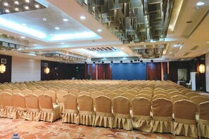 A large conference room with rows of chairs and a stage.