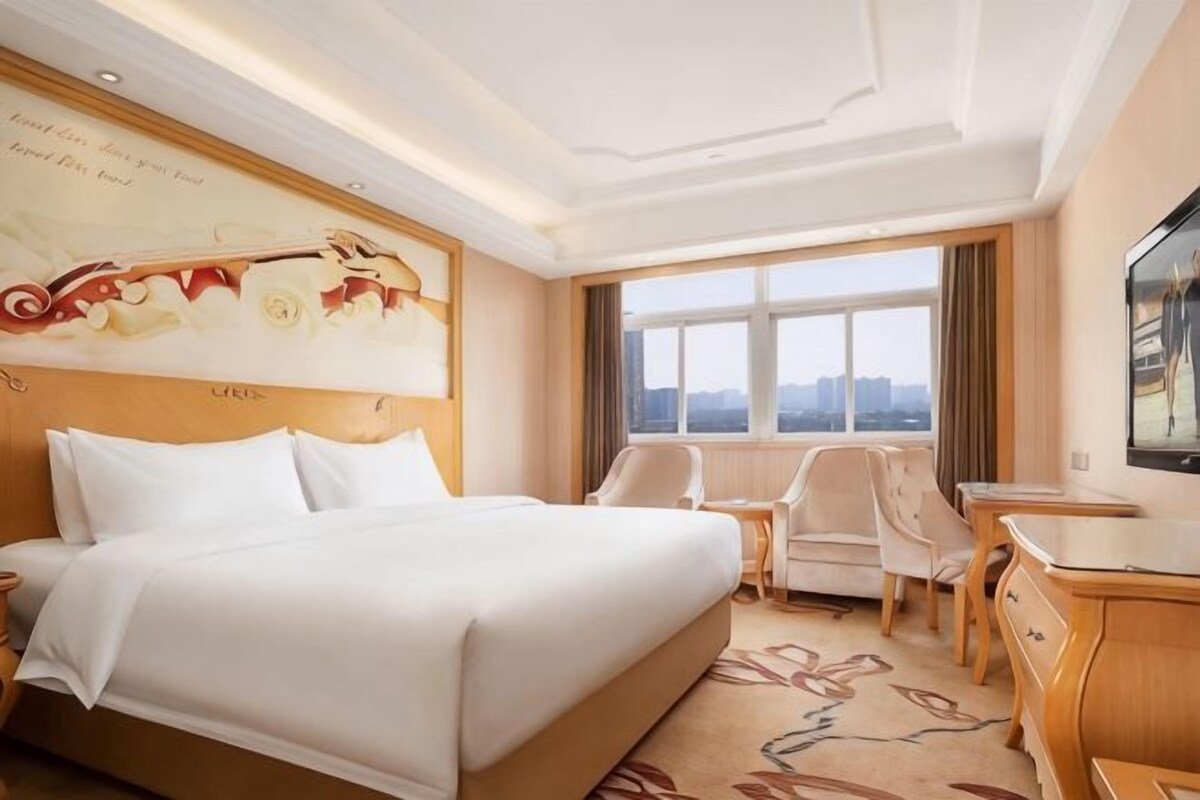 Una habitación de hotel con una cama grande, un escritorio, una silla y un televisor.